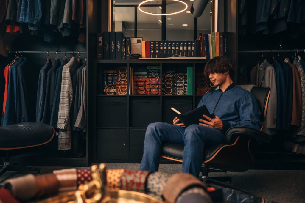 NOTA suit shop tailor, man in custom suit sitting on the chair, in suit shop setting, custom tailor, houndstooth tailors