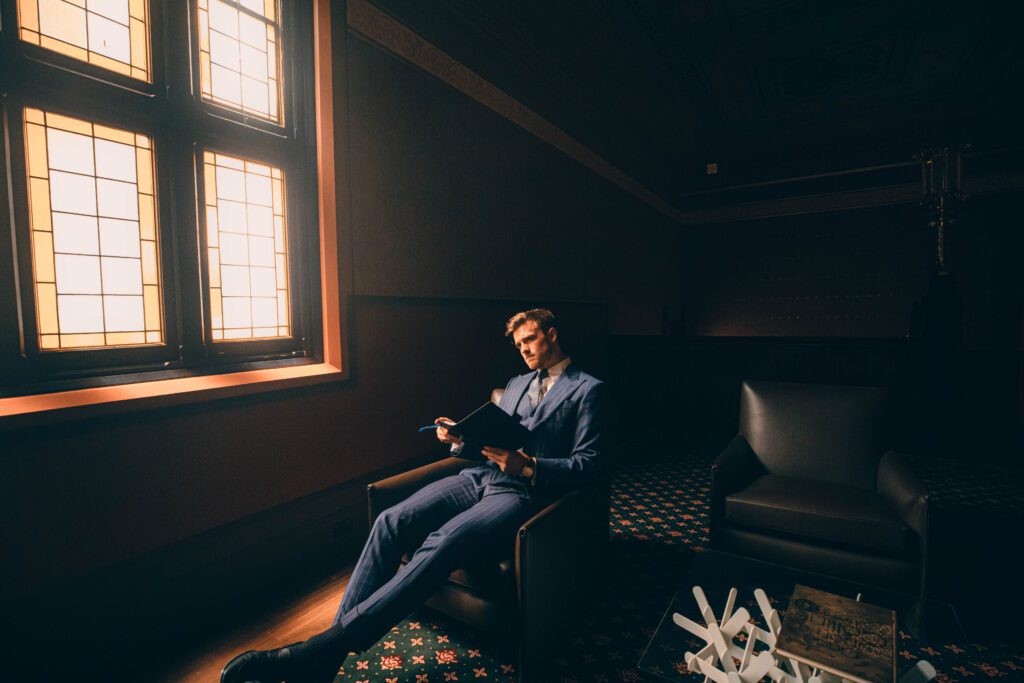 NOTA man in suit reading notebook, professional studio photo and model, in public in melbourne building, sitting next to building